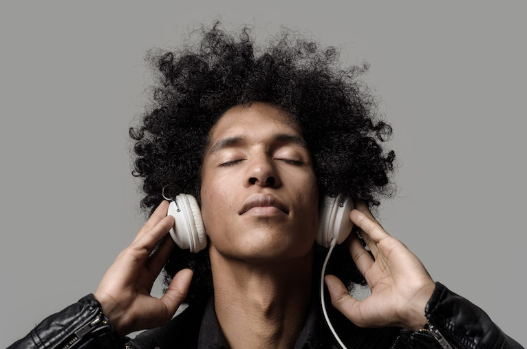 Retro man with afro listening to music on DJ headphones with eyes closed. isolated on grey background in studio.