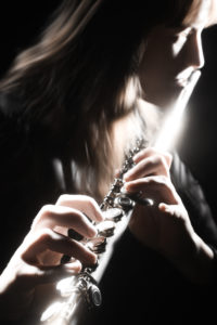 Musician performer flute playing. Flutist on the black