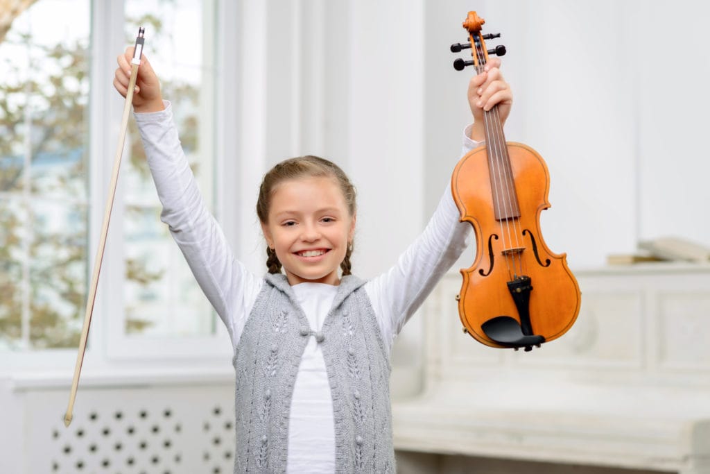 Young student holding up a violin victoriously