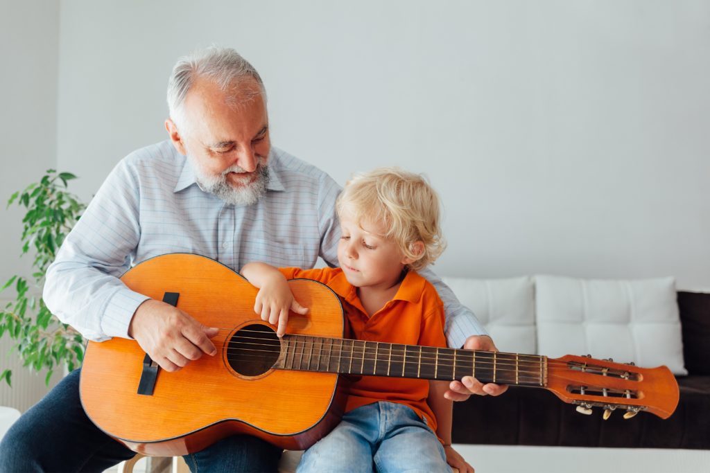Grandpa helping child learn guitar